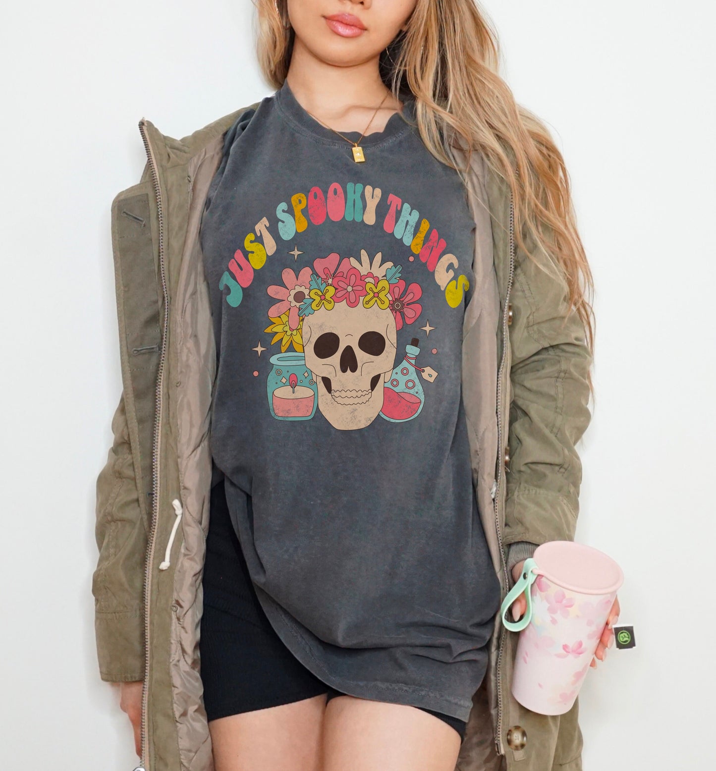 A t shirt in the color &quot;pepper&quot; with the words &quot;Just Spooky Things&quot; in Multicolor Retro Letters. Design features a skull with a flower crown, a candle, and a bottle of potion.