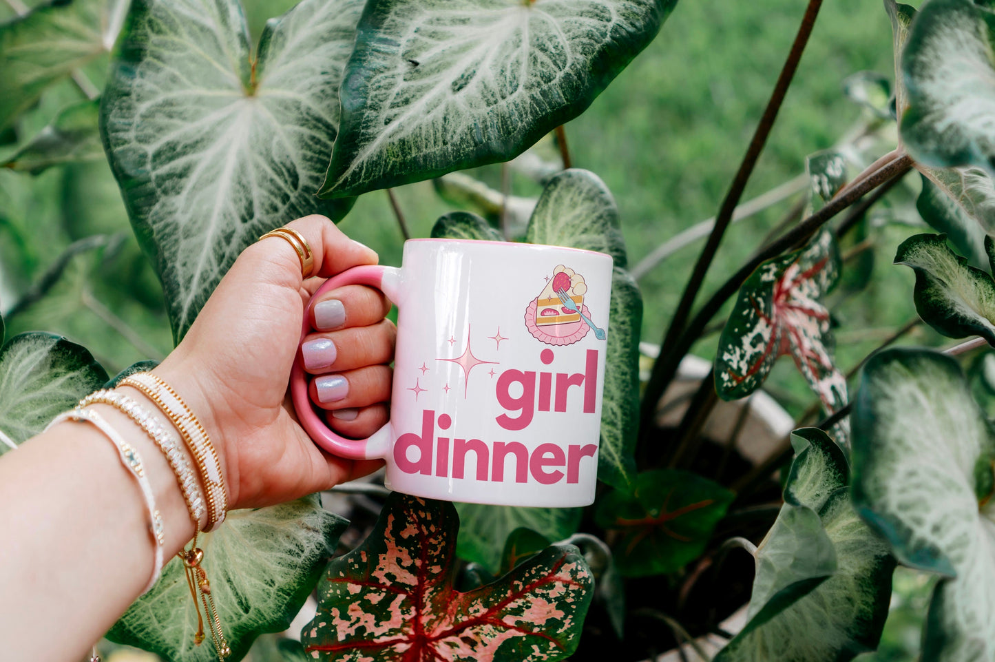 A White and Pink mug that reads &quot;Girl Dinner&quot;. Design features Pink lowercase fonts and a slice of Kawaii strawberry cake.