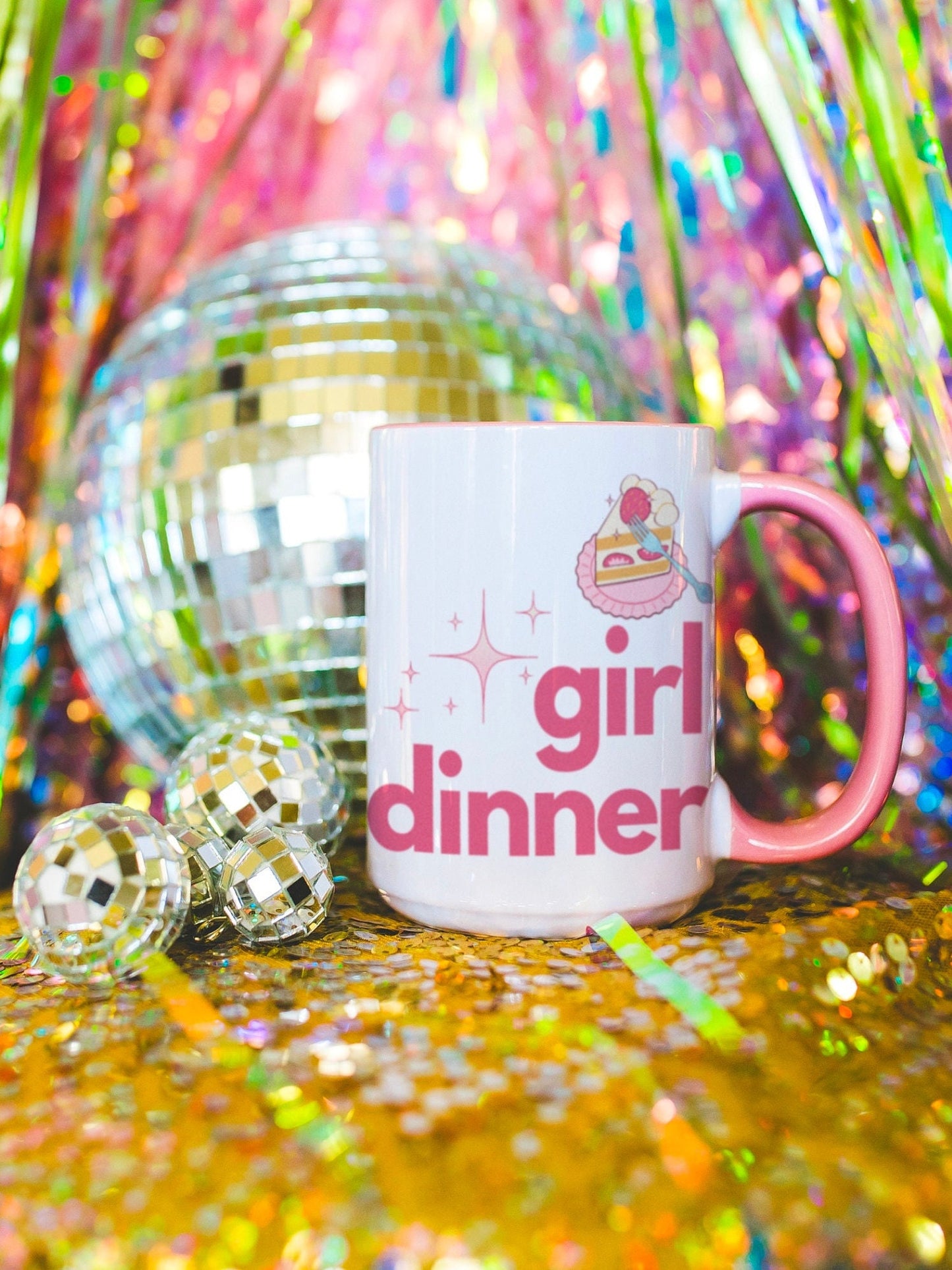 A White and Pink mug that reads &quot;Girl Dinner&quot;. Design features Pink lowercase fonts and a slice of Kawaii strawberry cake.