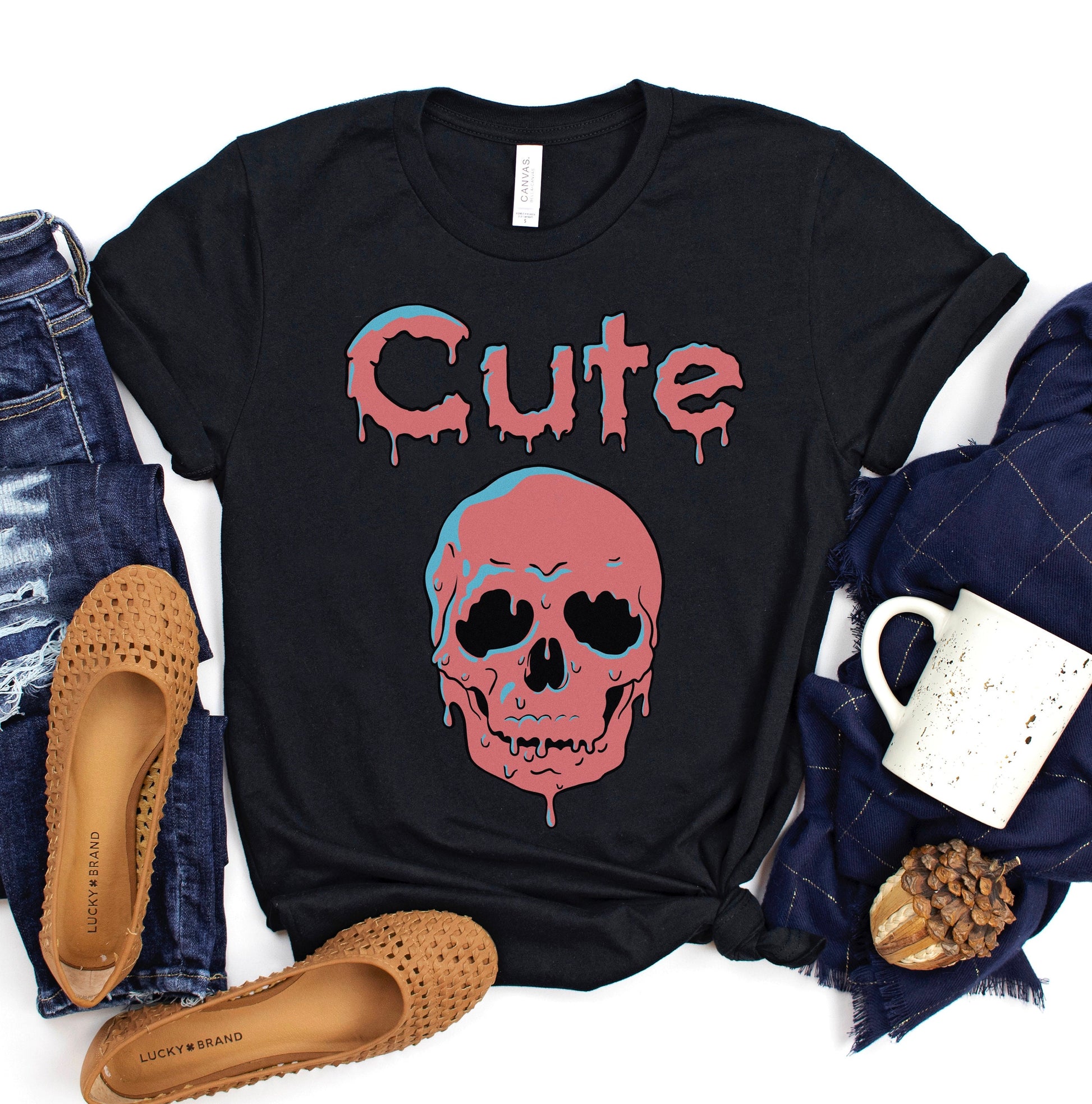 A black t shirt. Design on the shirt features a pink dripping skull with the word &quot;cute&quot; in pink drippy letters.